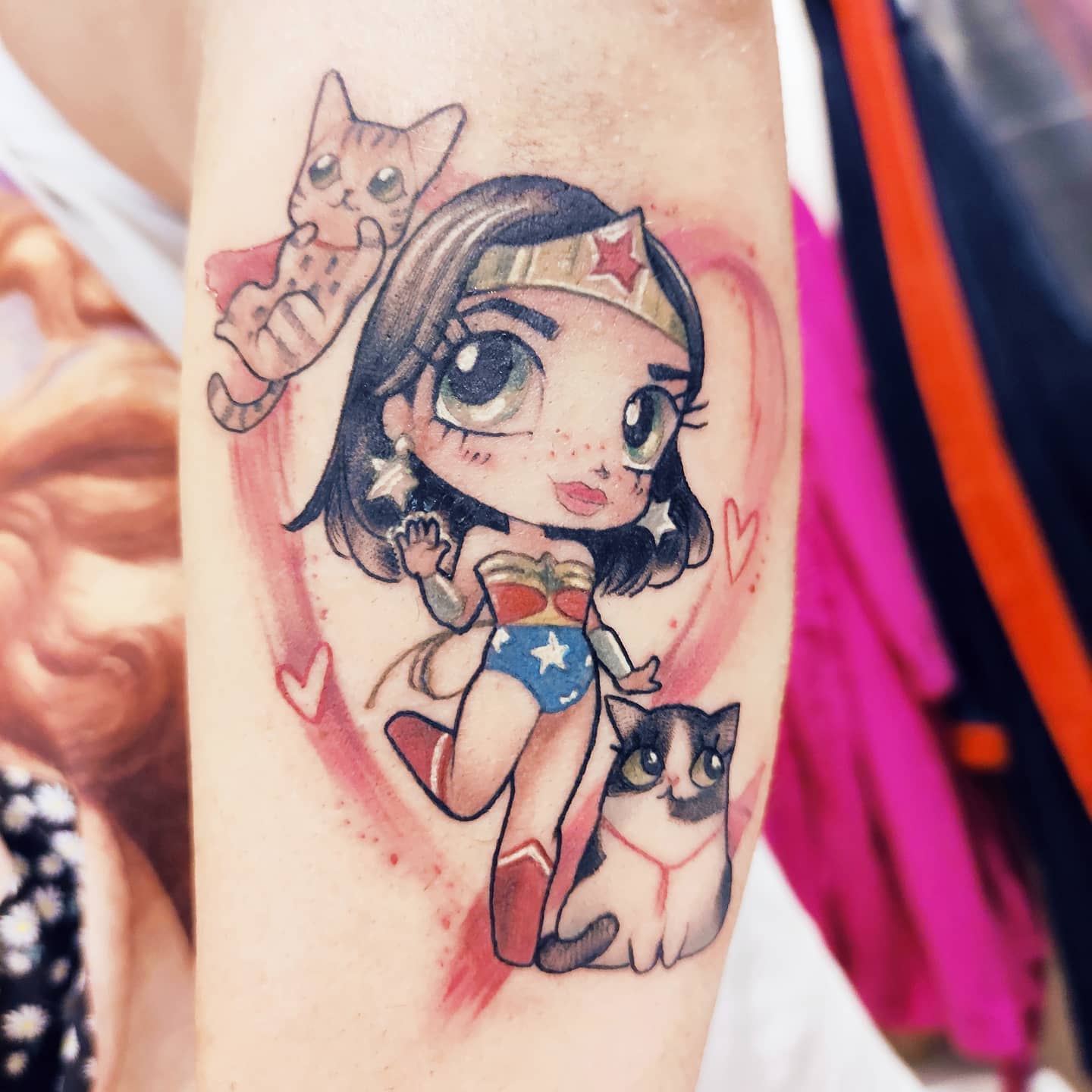 Chibi Wonder Woman tattoo in new school style, surrounded by cute cats and hearts, with large expressive eyes